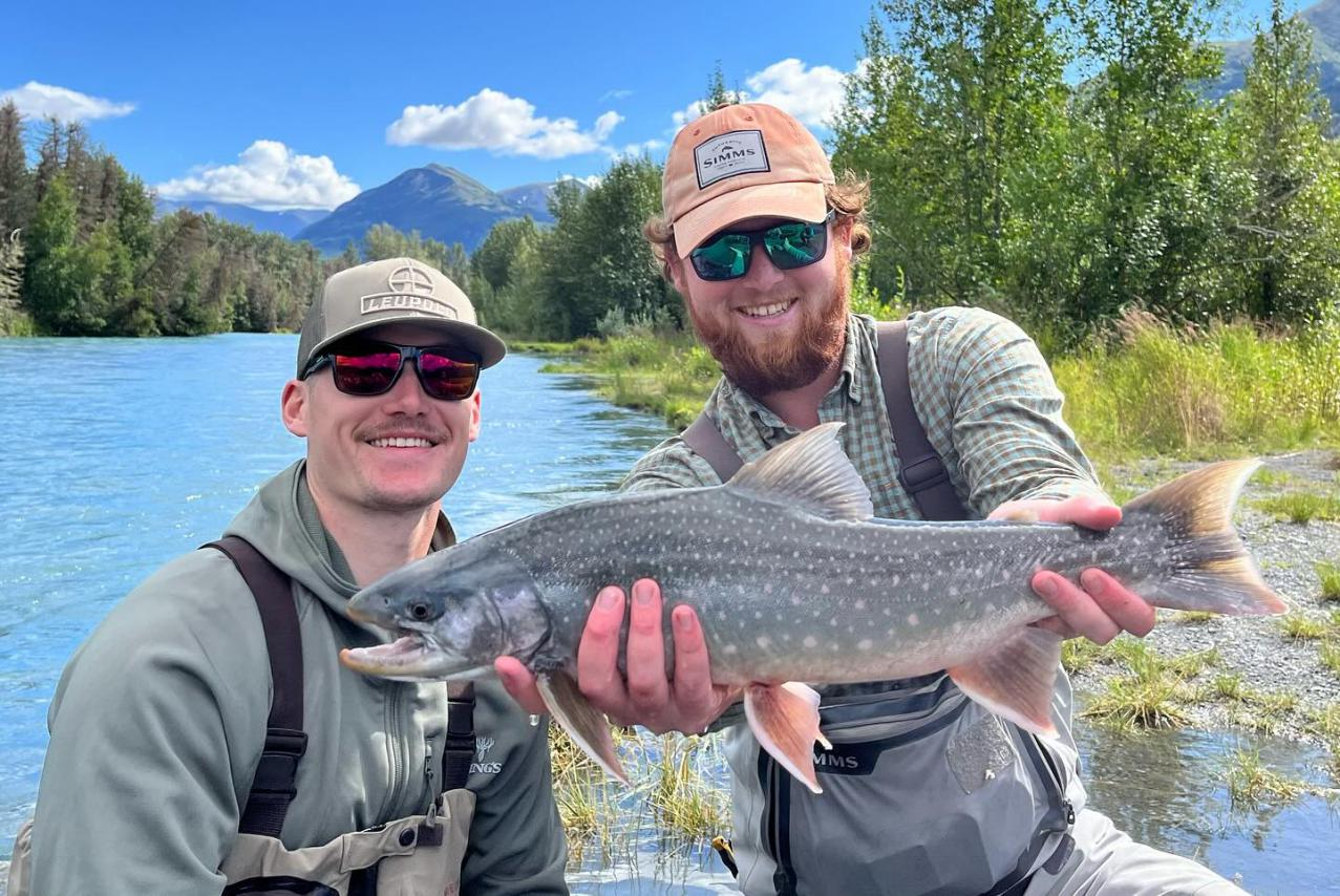 Two excited anglers celebrate their teamwork in landing a large Silver Salmon on the Kenai River in Alaska.